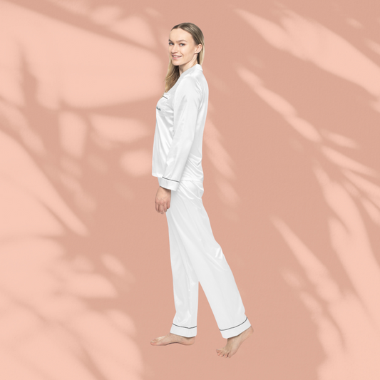 Side view of woman in white Soft & Sleek satin pyjamas walking barefoot, peach background.