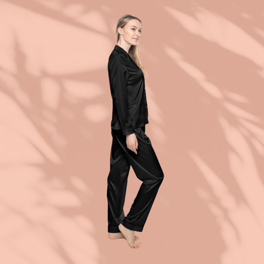 Side view of woman wearing black Soft & Sleek satin pyjamas, walking barefoot, peach background.