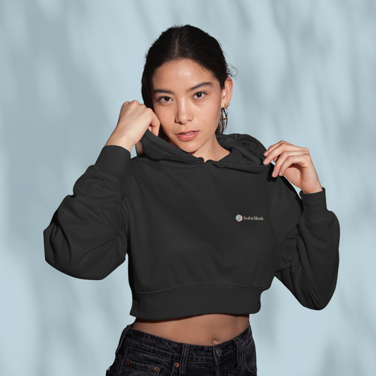 Person wearing a black cropped hoodie with a brand logo on a light gray background