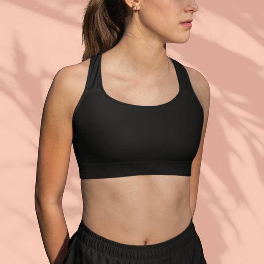 Front view of a woman in black Soft & Sleek racerback sports bra with mid-rise black shorts, peach background.