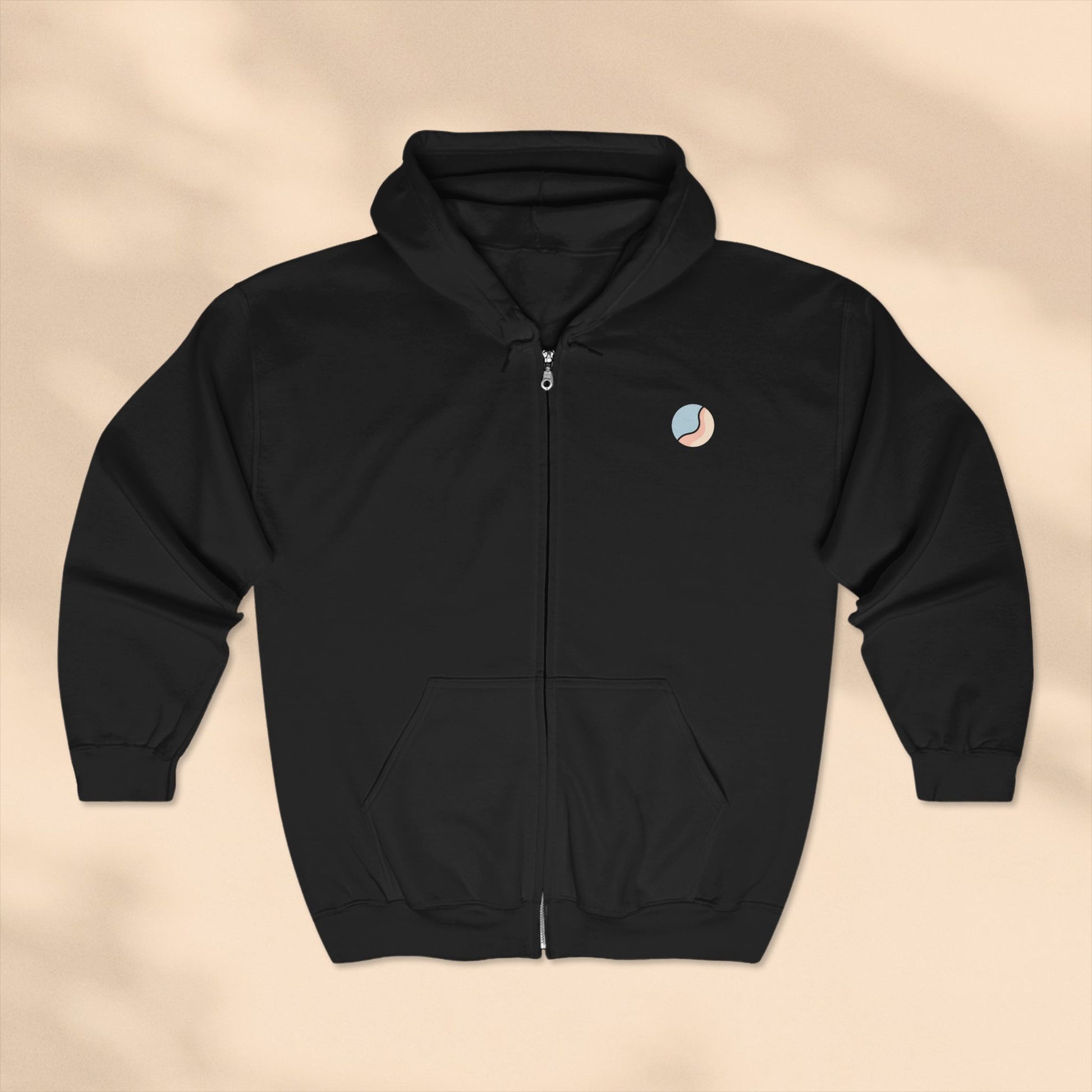 Black hoodie with a small logo on a beige background