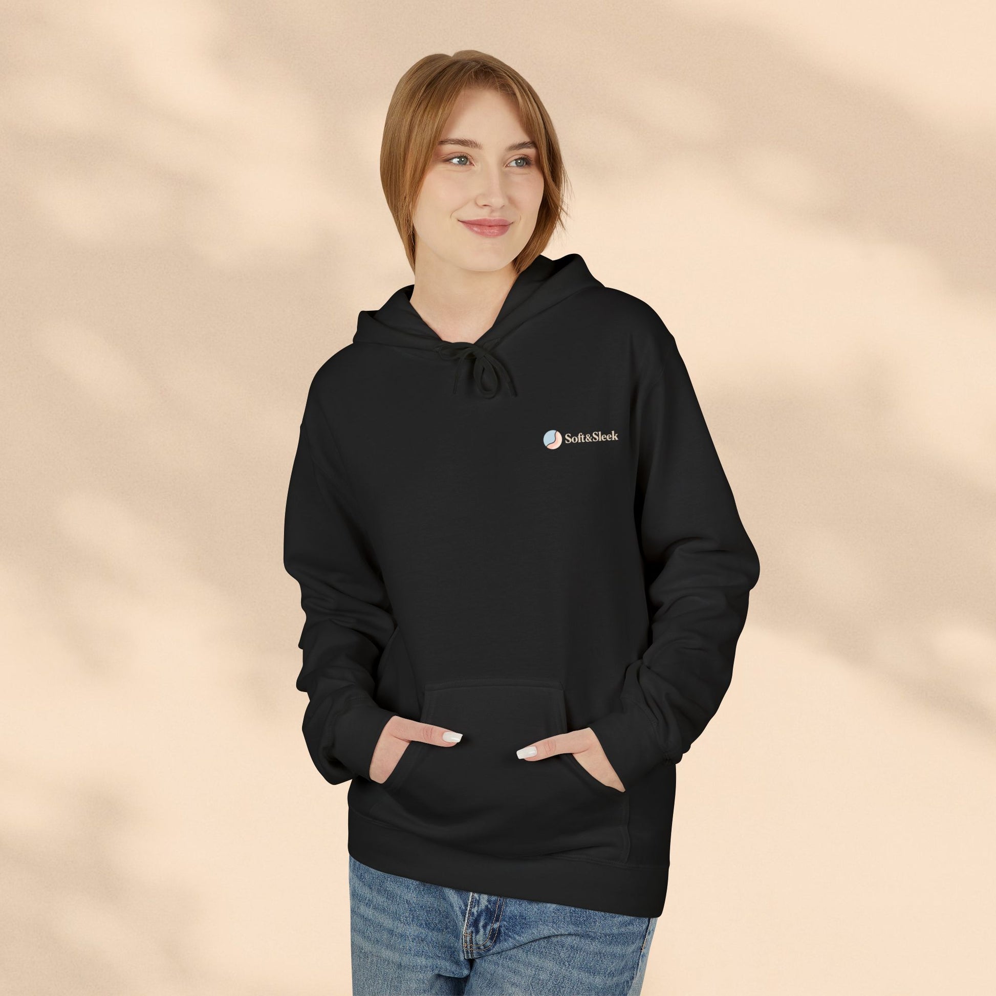 Person wearing a black hoodie with a logo on a beige background