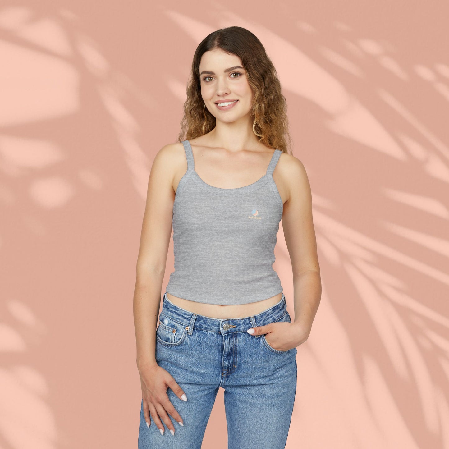 Woman wearing a gray tank top and blue jeans against a pink background