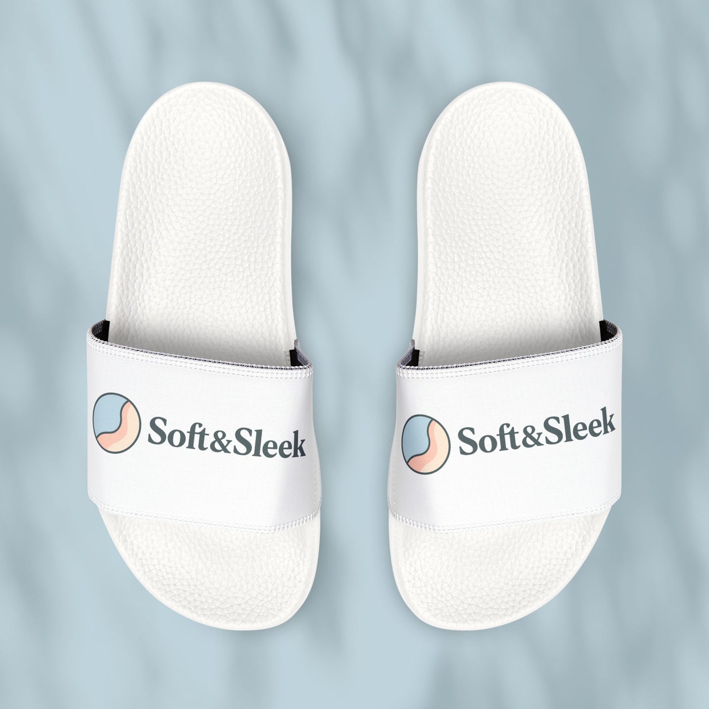 Flat lay of Soft & Sleek white slides placed side by side with visible logo and emblem, pale blue background
