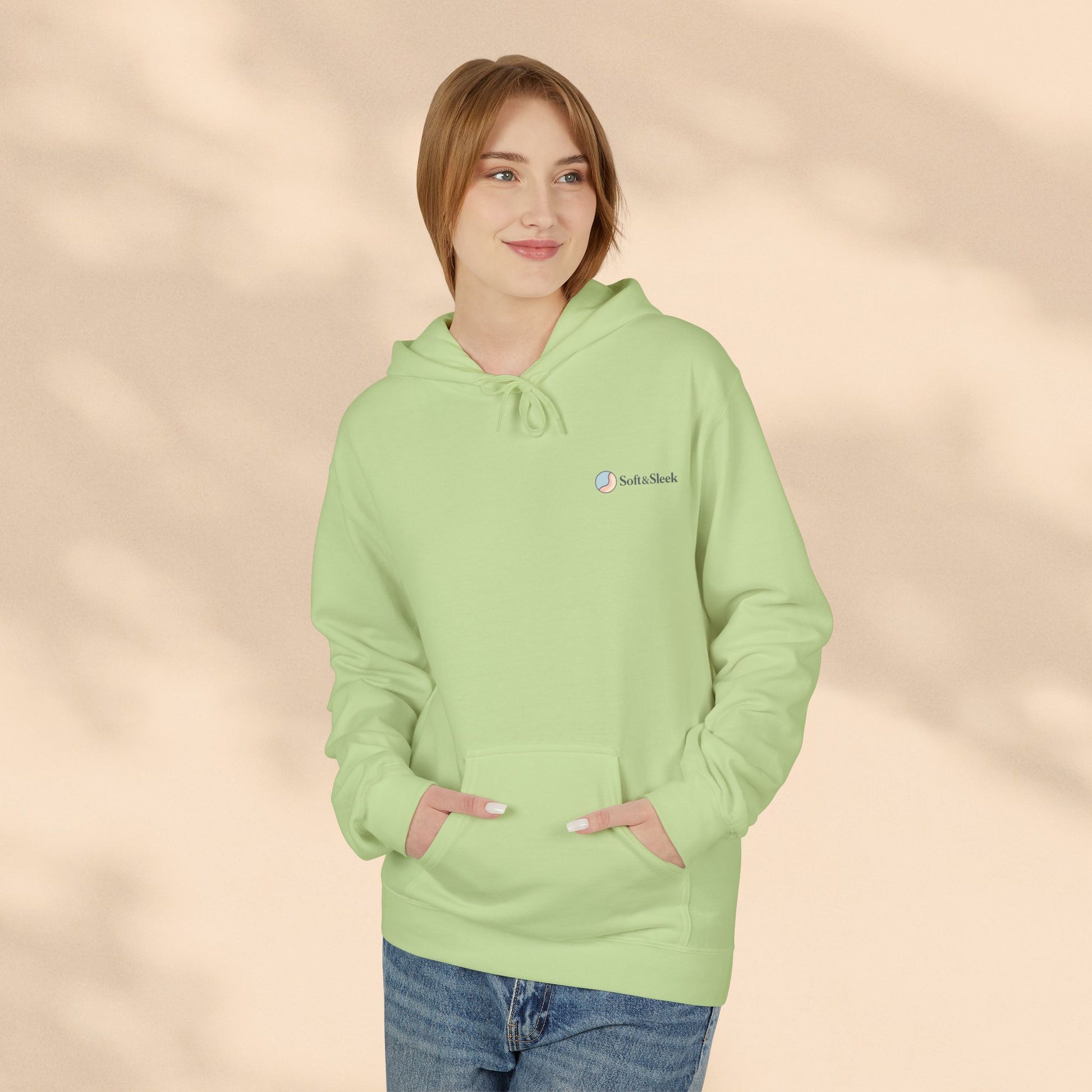 Person wearing a light green hoodie with a logo on a beige background