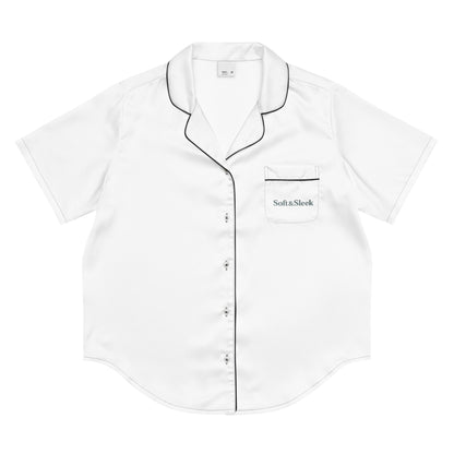 Flat lay of a white Soft & Sleek short-sleeve pyjama shirt with black piping and logo on the chest pocket.