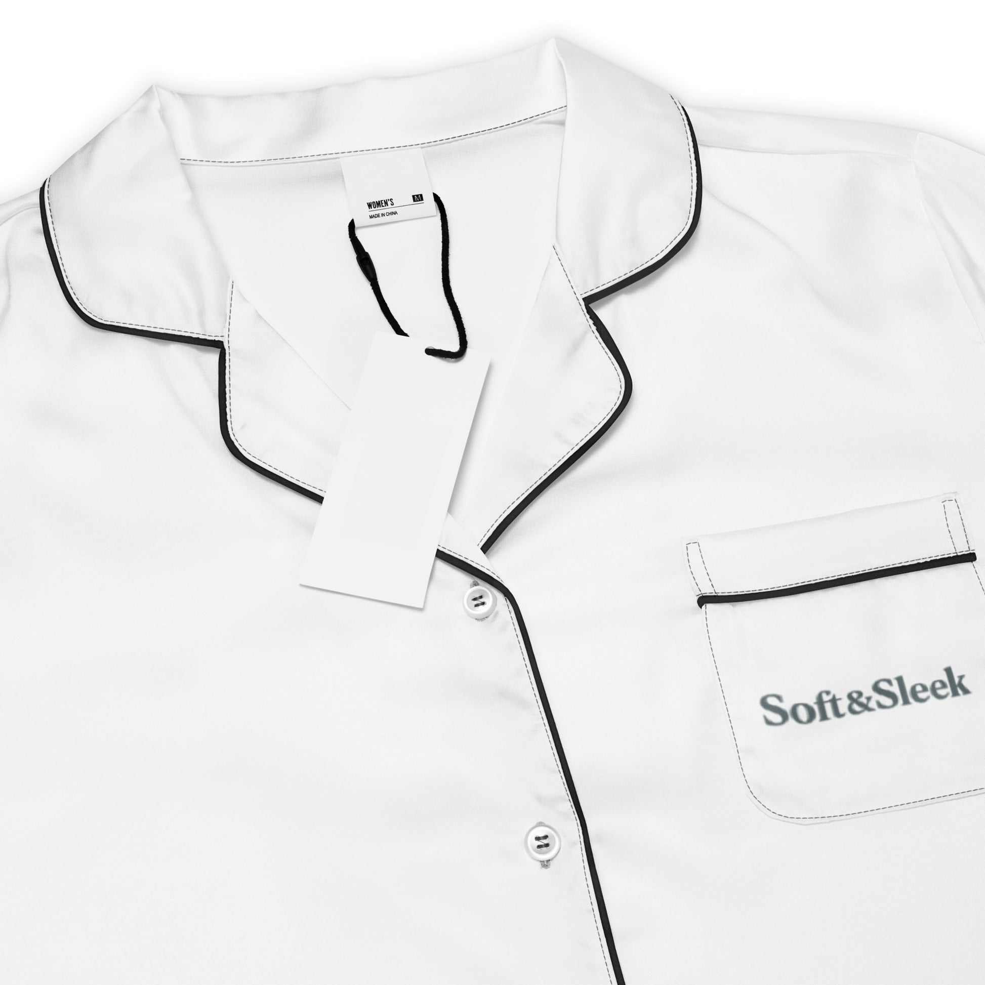 Close-up of the collar and chest pocket area on a Soft & Sleek white pyjama shirt with black piping and logo.
