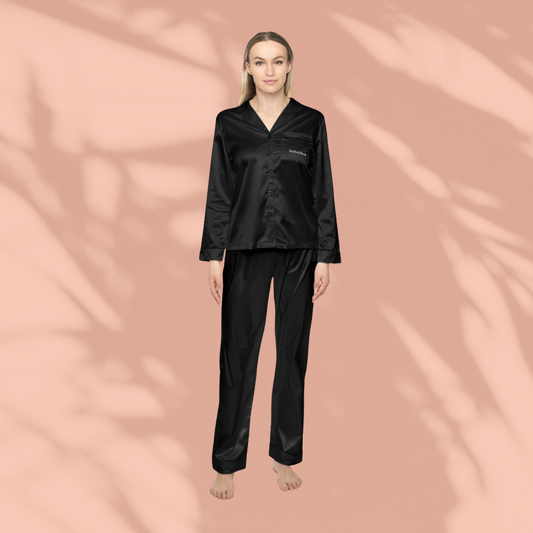 Person wearing a black satin pajama set on a pink background