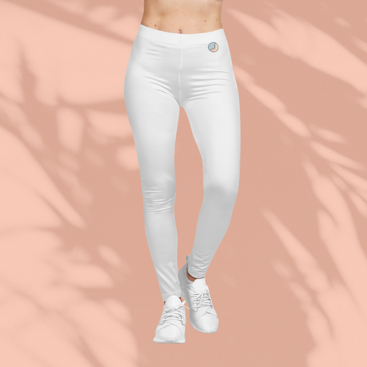 Front view of woman wearing white Soft & Sleek leggings with circular emblem, standing in white sneakers against a peach background