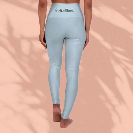 Rear view of woman in pastel blue Soft & Sleek seamless leggings with logo on waistband, standing barefoot, peach background