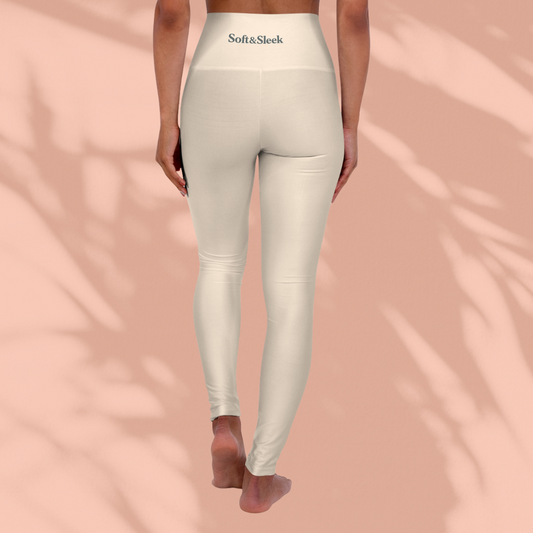Rear view of woman in cream Soft & Sleek leggings with logo on waistband, standing barefoot against a peach background
