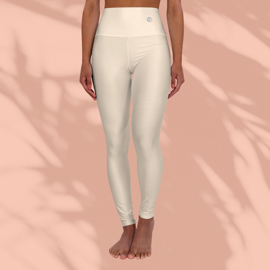 Front view of woman wearing cream Soft & Sleek seamless leggings with circular emblem on waistband, barefoot, peach background