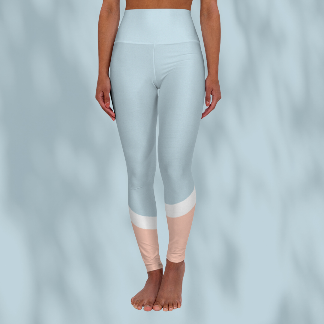 Front view of woman wearing pastel blue cropped Soft & Sleek leggings with peach and white colour-block detail at calves, pale blue background