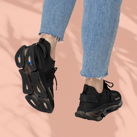 Angled view of black Soft & Sleek trainers in motion worn with jeans, peach background.