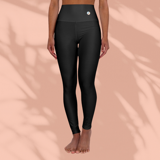 Front view of a woman wearing black Soft & Sleek high-waisted leggings, standing barefoot against a peach background.